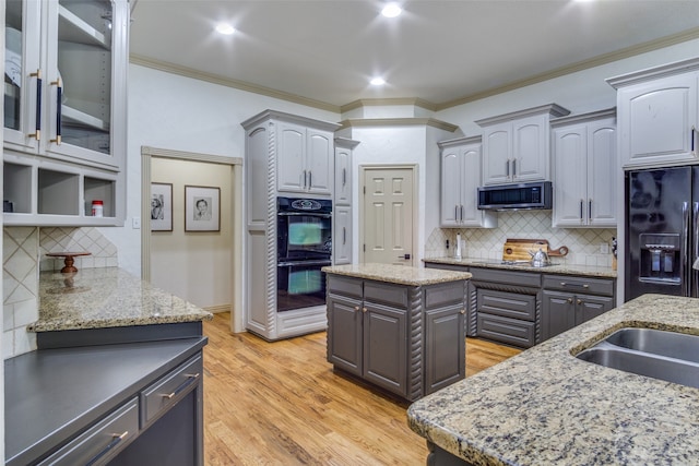 kitchen with gray cabinetry, black appliances, and a center island