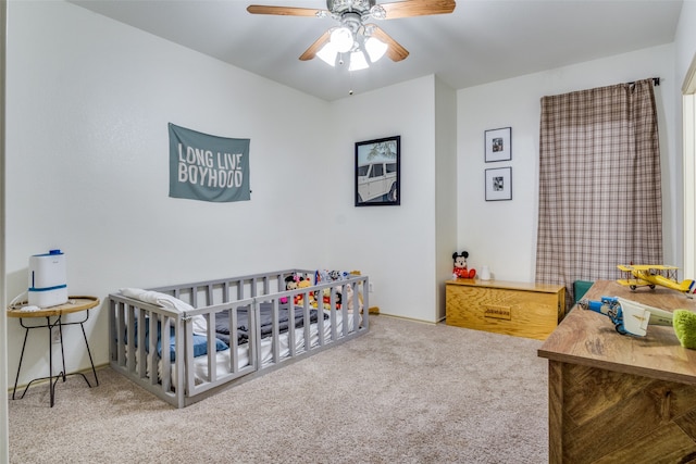 carpeted bedroom featuring ceiling fan and a crib