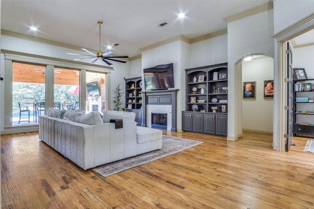 living room with ceiling fan, ornamental molding, and light hardwood / wood-style floors