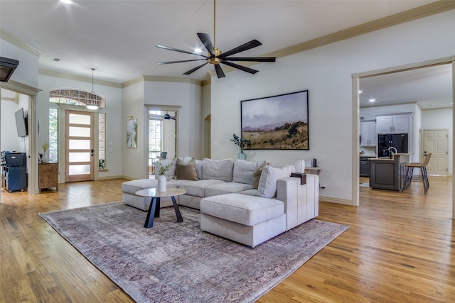 living room with light wood-type flooring, crown molding, and ceiling fan