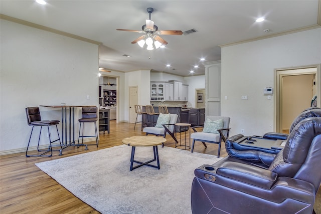 living room with crown molding, ceiling fan, and light hardwood / wood-style flooring