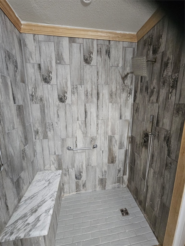 bathroom with a textured ceiling and a tile shower