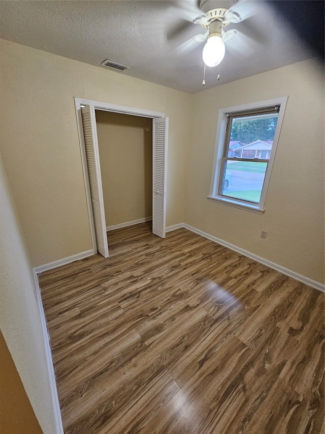 unfurnished bedroom featuring a closet, wood-type flooring, and ceiling fan