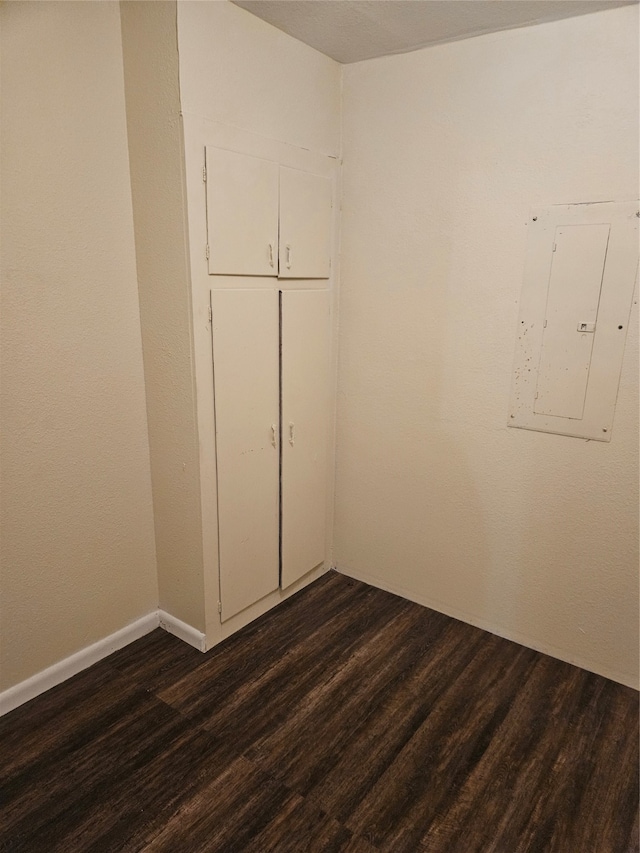 spare room featuring electric panel and dark hardwood / wood-style flooring