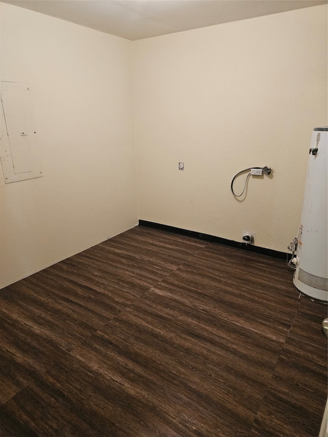 unfurnished room with electric panel, dark hardwood / wood-style floors, and water heater