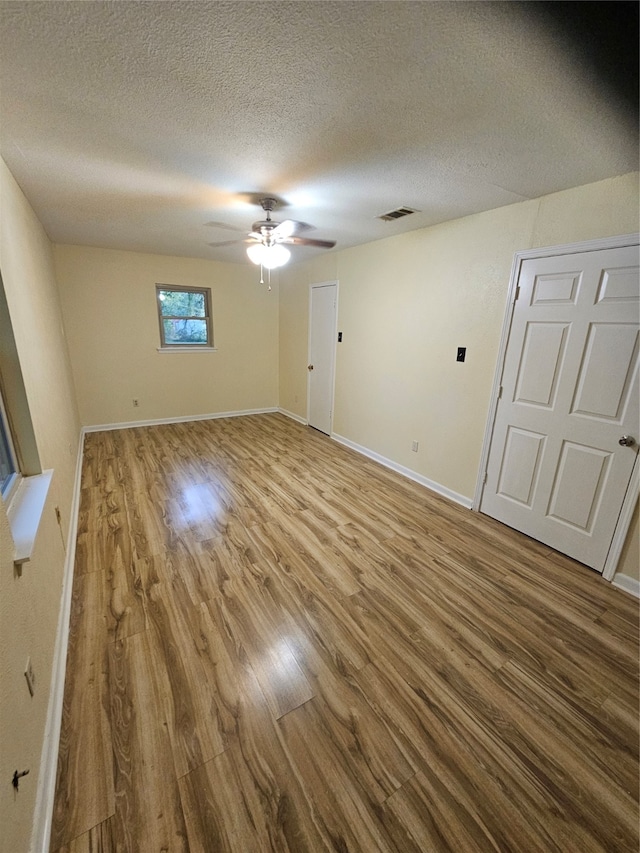 spare room with ceiling fan, a textured ceiling, and hardwood / wood-style floors