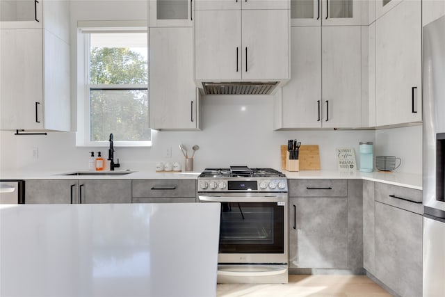 kitchen featuring stainless steel gas range, sink, and extractor fan