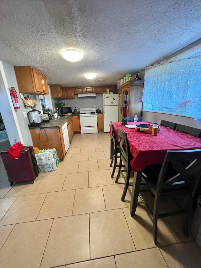 kitchen with white appliances, light tile patterned floors, and a textured ceiling