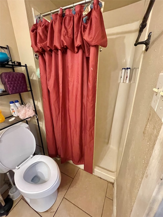 bathroom with a shower with curtain, toilet, and tile patterned floors