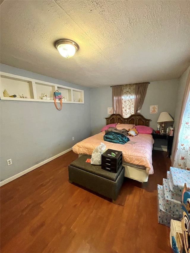 bedroom with dark hardwood / wood-style floors and a textured ceiling