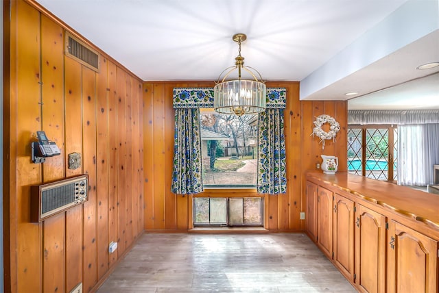 dining room featuring heating unit, light hardwood / wood-style flooring, a notable chandelier, and wood walls