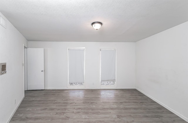 unfurnished room with wood-type flooring and a textured ceiling