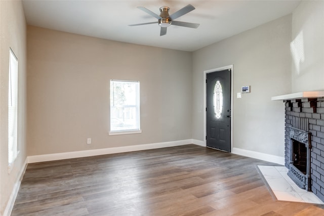 foyer entrance with ceiling fan, a fireplace, and hardwood / wood-style floors