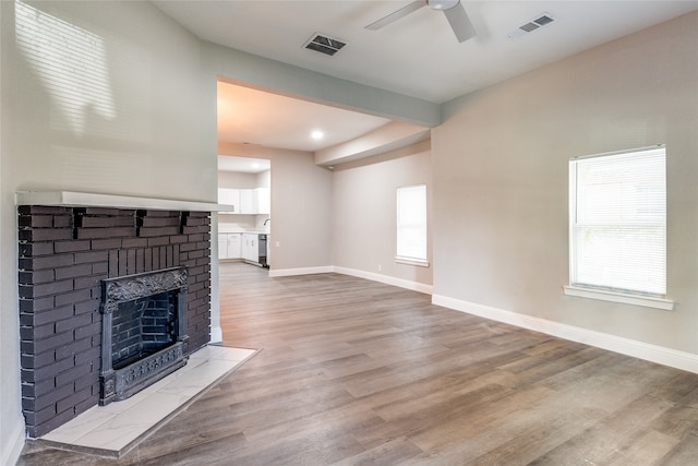 living room featuring light wood-type flooring, ceiling fan, and a fireplace