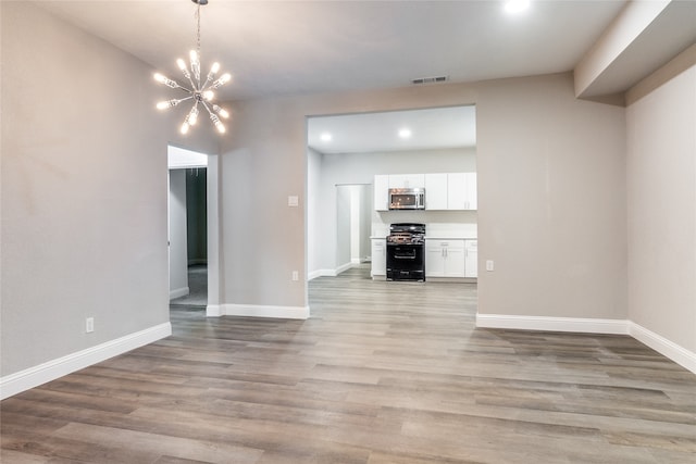 unfurnished living room with a notable chandelier and light hardwood / wood-style flooring