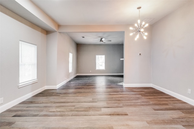 unfurnished room featuring wood-type flooring and ceiling fan with notable chandelier