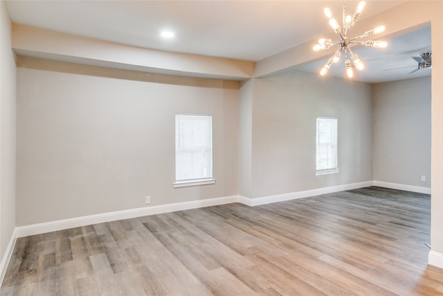 empty room with light wood-type flooring and ceiling fan with notable chandelier