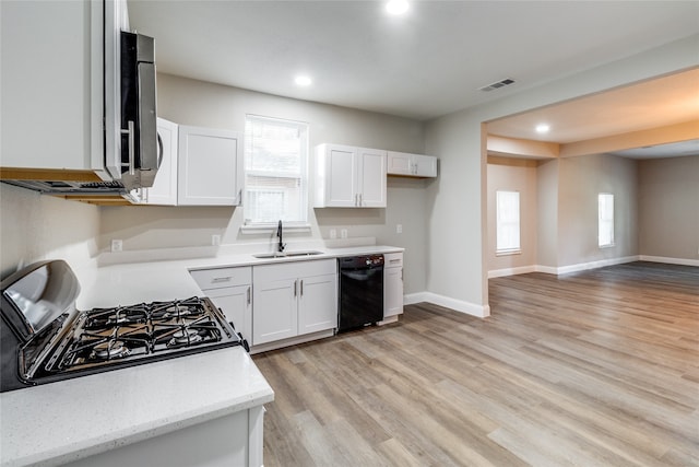 kitchen featuring range with gas stovetop, black dishwasher, light hardwood / wood-style floors, sink, and white cabinets