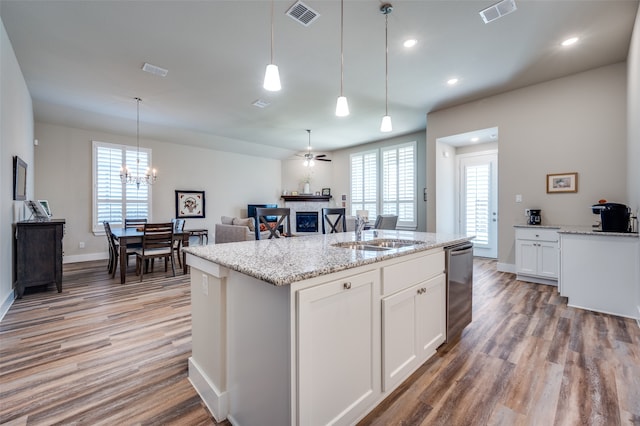 kitchen with pendant lighting, white cabinets, sink, light hardwood / wood-style flooring, and an island with sink