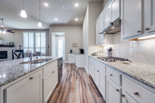 kitchen featuring pendant lighting, sink, dark hardwood / wood-style floors, a fireplace, and white cabinetry