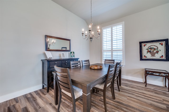 dining space featuring hardwood / wood-style flooring, lofted ceiling, and a notable chandelier