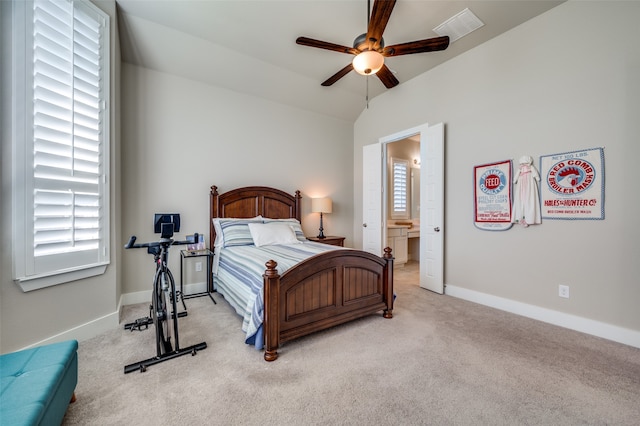 bedroom with ceiling fan, multiple windows, connected bathroom, and vaulted ceiling