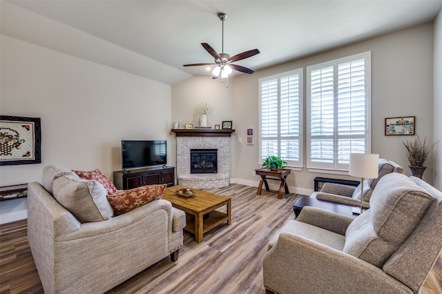 living room with ceiling fan, a fireplace, wood-type flooring, and vaulted ceiling