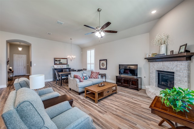 living room with ceiling fan with notable chandelier, light hardwood / wood-style floors, lofted ceiling, and a fireplace