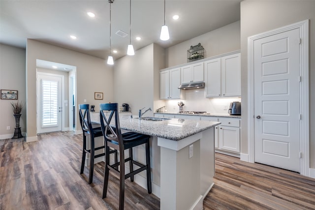 kitchen with pendant lighting, light stone countertops, white cabinetry, and sink