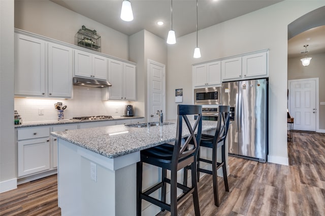 kitchen featuring sink, decorative light fixtures, a center island with sink, white cabinets, and appliances with stainless steel finishes