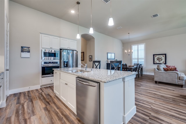 kitchen featuring sink, stainless steel appliances, decorative light fixtures, a center island with sink, and white cabinets