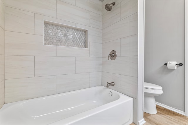 bathroom featuring tiled shower / bath combo, hardwood / wood-style flooring, and toilet