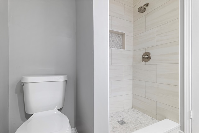 bathroom with tiled shower and toilet