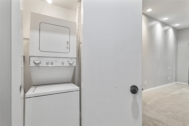 clothes washing area with stacked washer / dryer and carpet