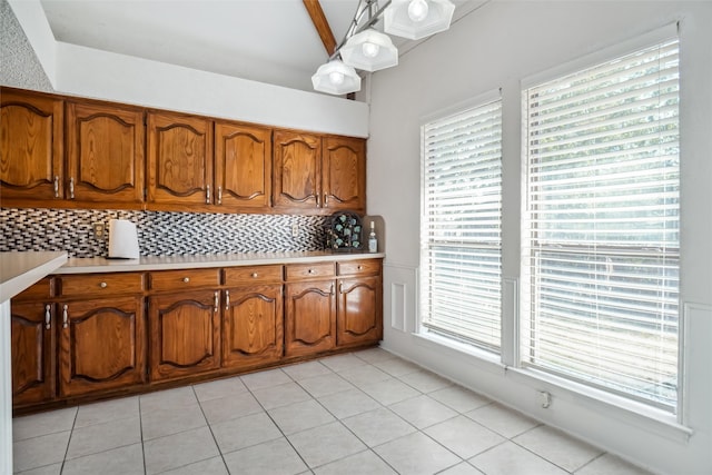 kitchen with light tile patterned flooring, tasteful backsplash, beamed ceiling, and hanging light fixtures