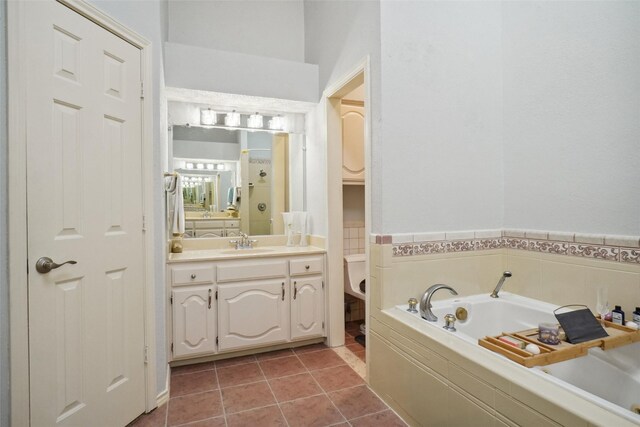 bathroom featuring vanity, a textured ceiling, tiled tub, and tile patterned floors