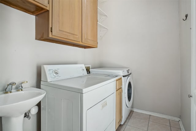 laundry area featuring cabinets, washer and dryer, sink, and light tile patterned floors