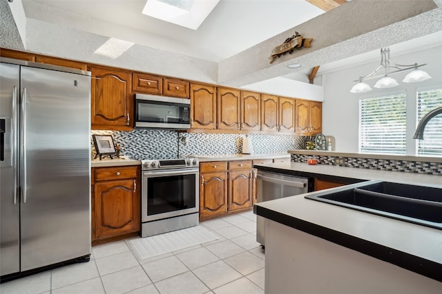 kitchen with tasteful backsplash, light tile patterned floors, sink, pendant lighting, and stainless steel appliances