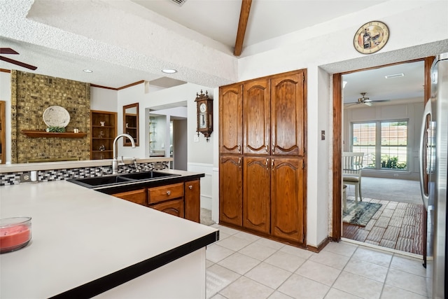 kitchen featuring beamed ceiling, sink, light tile patterned floors, a textured ceiling, and stainless steel refrigerator