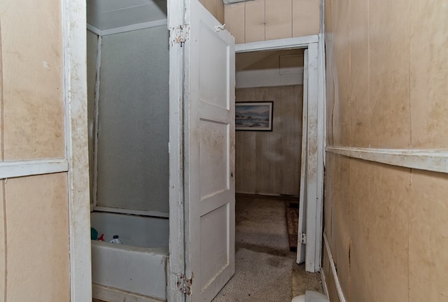 bathroom featuring wooden walls and a bathing tub