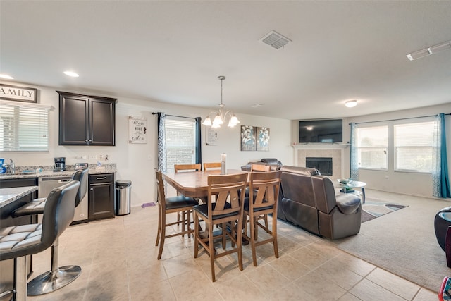 dining room featuring an inviting chandelier, a tile fireplace, and light tile patterned floors