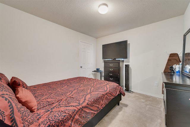 bedroom featuring a textured ceiling and light colored carpet