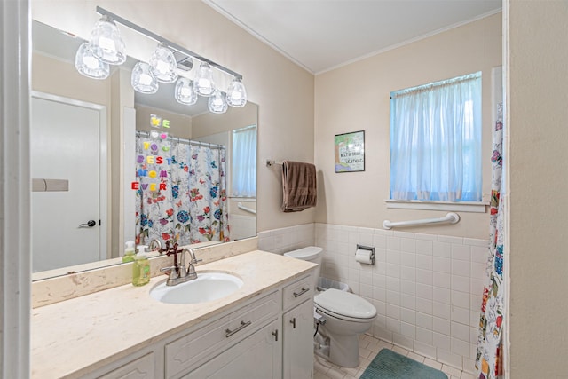 bathroom with tile walls, toilet, wainscoting, vanity, and tile patterned floors