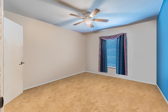 spare room with light carpet, ceiling fan, and baseboards