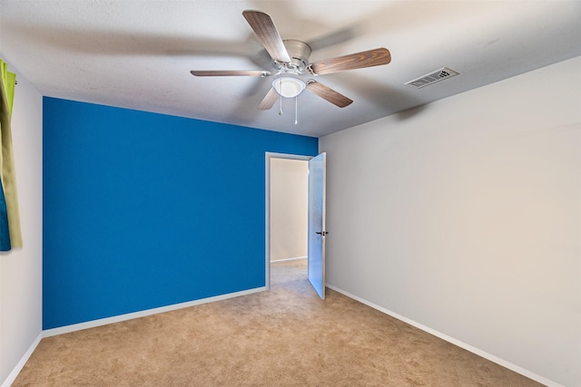 spare room featuring carpet floors, visible vents, ceiling fan, and baseboards