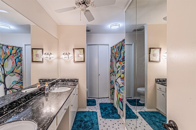 bathroom with visible vents, double vanity, a sink, and toilet