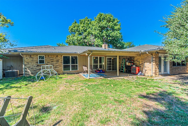 rear view of property with a patio, a lawn, and brick siding