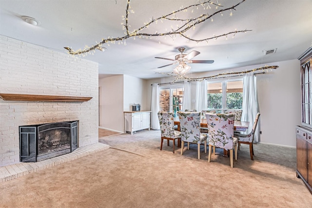 dining area featuring visible vents, baseboards, ceiling fan, carpet flooring, and a brick fireplace