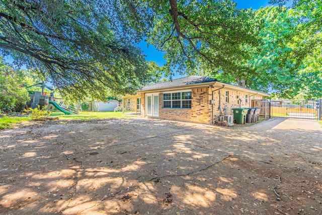 exterior space with a playground, brick siding, and fence