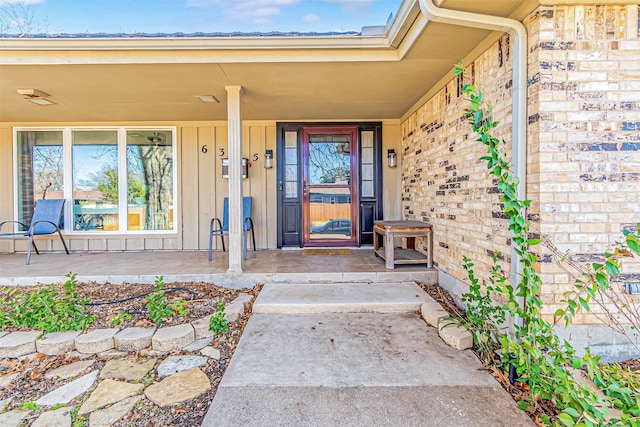 property entrance featuring board and batten siding, covered porch, and brick siding